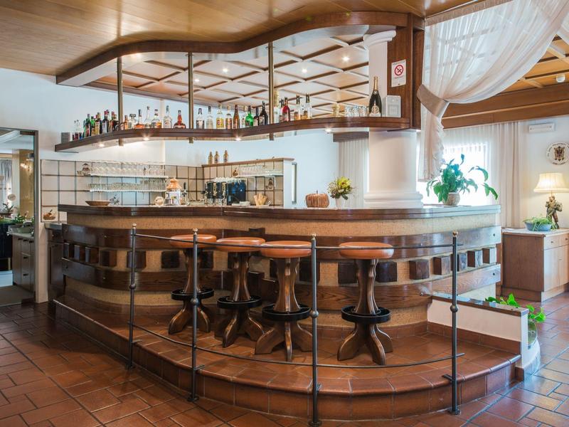 Gezellige hotelbar met houten lambrisering, krukken en decoratieve planten binnen.