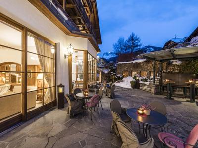 Hotel terrace with tables and chairs at dusk, cozy lighting and mountain view