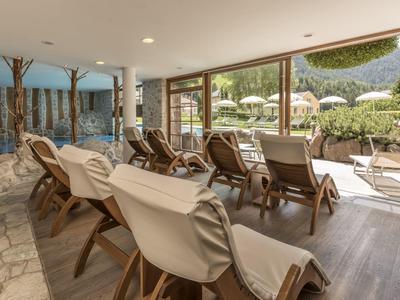 Covered terrace with lounge chairs overlooking mountains and garden.