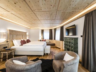 Modern hotel room with two beds, seating area, and wooden floor.