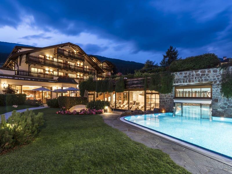 Luxury hotel with illuminated pool and manicured garden at dusk