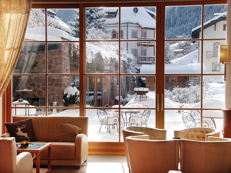 Cozy seating area by large windows overlooking snowy mountain landscape and terrace.