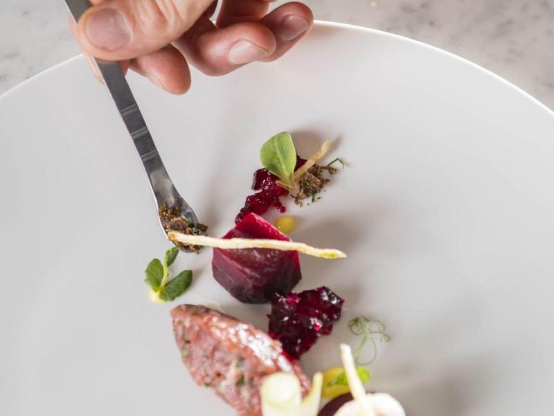 Delicately arranged gourmet plate with small portions and edible flowers.
