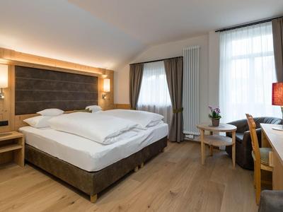 Camera d'hotel moderna con letto matrimoniale, pannelli in legno e zona salotto accogliente.