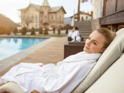 Donna rilassata in accappatoio su lettino vicino alla piscina dell'hotel.