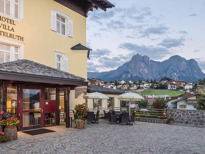 Hotel giallo con terrazza e vista sulle montagne al tramonto.