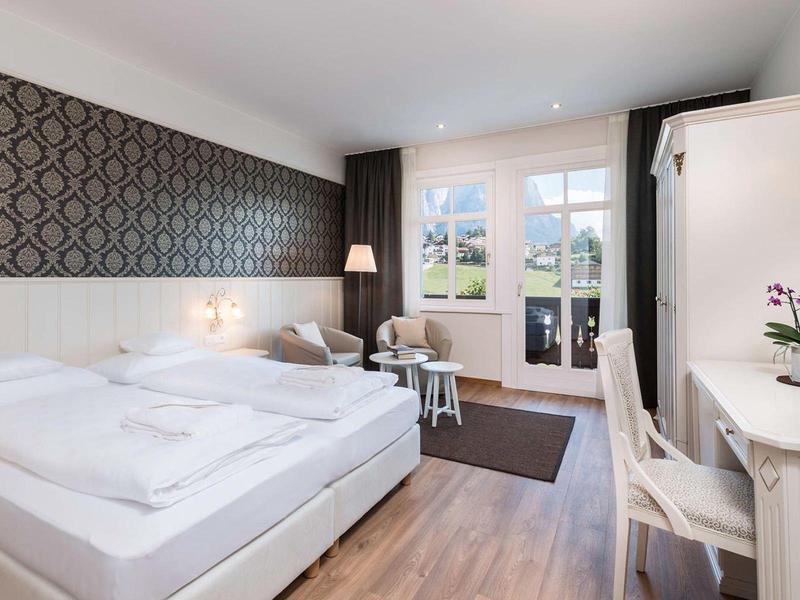 Camera d'hotel moderna con letto matrimoniale, scrivania e balcone con vista.