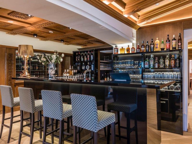 Bar elegante dell'hotel con legno scuro, posti a sedere confortevoli e scaffali di vini ben forniti.