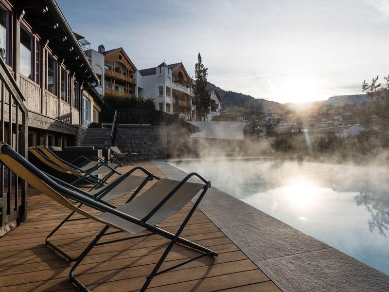 Sdraio vuote accanto a una piscina fumante all'alba in un ambiente montano.