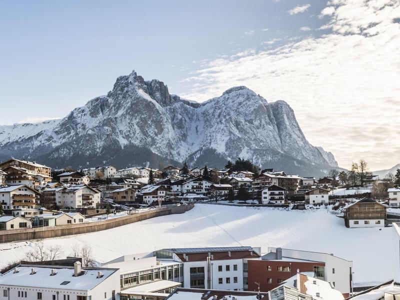 Villaggio innevato con imponente scenario montano sotto cielo limpido.
