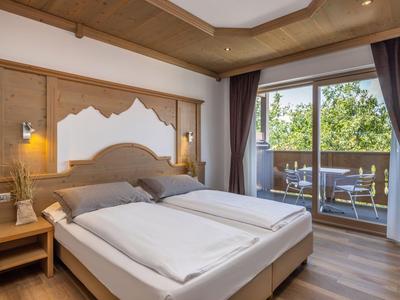 Camera d'hotel accogliente con letto matrimoniale e balcone con vista sul verde.