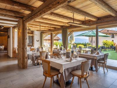 Pohodlná restaurace s dřevěnými trámky a stoly s bílými ubrusy vedle zahrady.