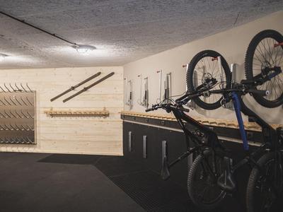 Interior space with wall mounts and several displayed bicycles, wooden walls and carpeted floor.