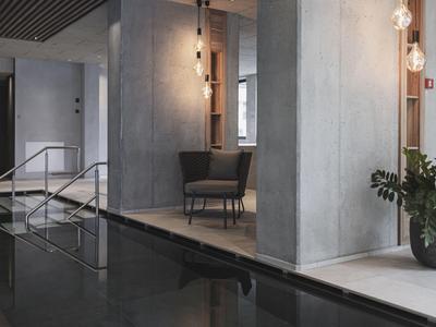 Modern hotel area with dark water pool, chair, and minimalist decor.