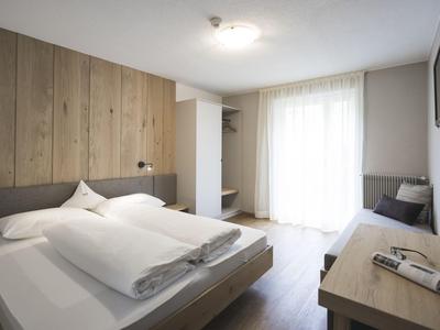 Modern hotel room with double bed, desk, and access to a balcony.