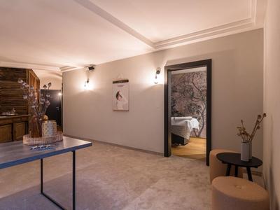 Moderner Raum mit Tisch, Holzmöbeln, Kunst an Wänden und Blick ins Schlafzimmer.