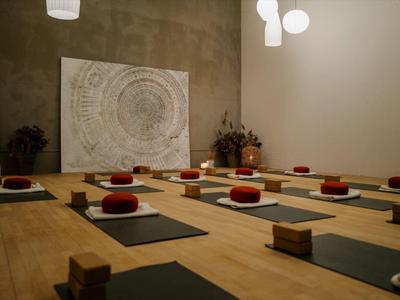 Meditationsraum mit Matten, Kissen und gedämpftem Licht in einem modernen Interieur.