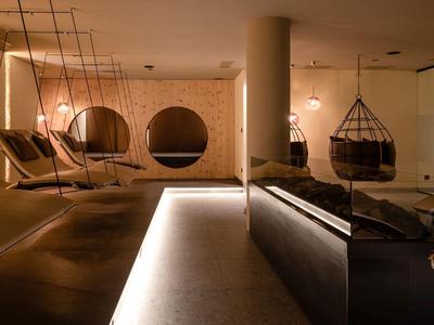 Gemütlicher Raum mit Hängesesseln, weicher Beleuchtung und modernem, warmem Holzdesign.