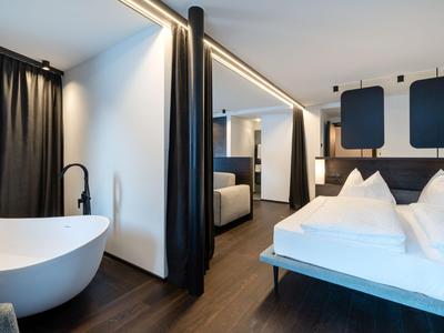 Habitación de hotel moderna con bañera redonda y cama doble acogedora.