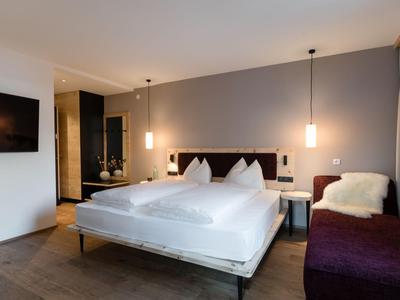 Chambre moderne avec lit double, lampes murales et téléviseur fixé au mur.