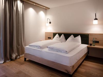 Habitación de hotel bien iluminada con cama doble, mesitas de noche y cortinas.