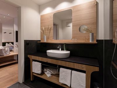 Baño moderno con lavabo, espejo y toallas en una habitación de hotel.