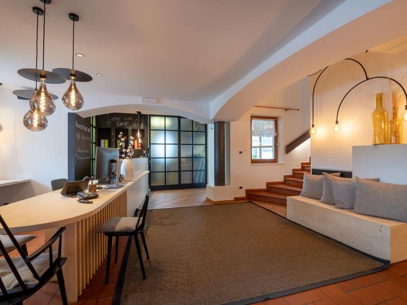 Moderner Wohnraum mit rustikalen Elementen, Essbereich, Sofa, Treppe und warmem Lichtakzent.