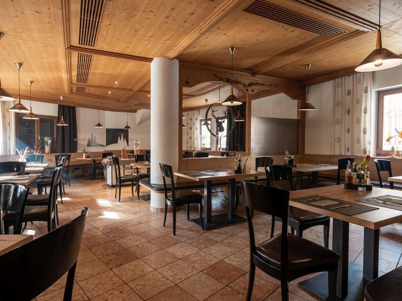 Gemütliches Restaurant mit Holzbalken, gemusterten Bodenfliesen und dunkelbraunen Stühlen.