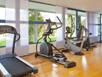 Nowoczesna siłownia z bieżnią i innymi urządzeniami cardio przy dużych oknach.