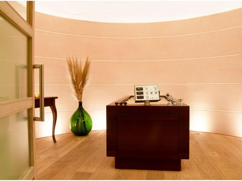 Kleiner Empfangsbereich mit braunem Holzschreibtisch, grünem Vase und beige Wandgestaltung.