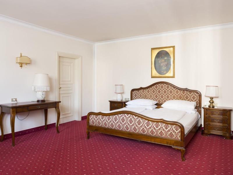 Hell eingerichtetes Schlafzimmer mit rotem Teppich, Doppelbett und zwei Nachttischen.