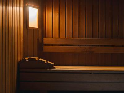 Holzsauna mit warmem Licht, Holzbänken und einem Kopfstützkissen an der Wand.