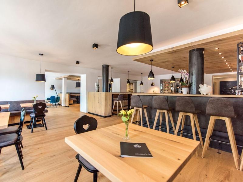 Helles Café mit Holzmöbeln, schwarzen Lampen und gemütlicher, moderner Atmosphäre.