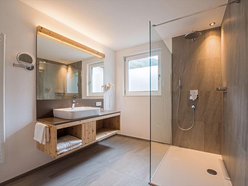 Modernes Badezimmer mit großer Dusche, Doppelwaschbecken und hellem Holzdekor.