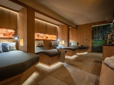 Modern gestalteter Ruheraum mit Holzvertäfelung, drei großen Liegen und entspannender Beleuchtung.