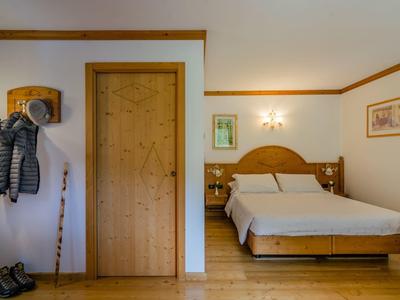 Gemütliches Schlafzimmer mit Holzmöbeln, Doppelbett, Garderobe und dekorativen Bildern an der Wand.
