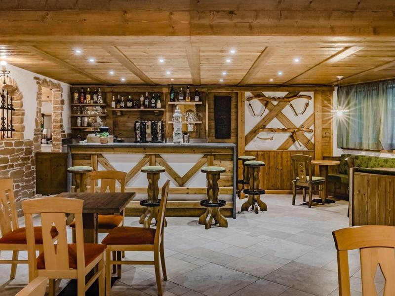 Rustikale Gaststube mit Holzmöbeln, Bartresen und Steinwänden in warmem Ambiente.