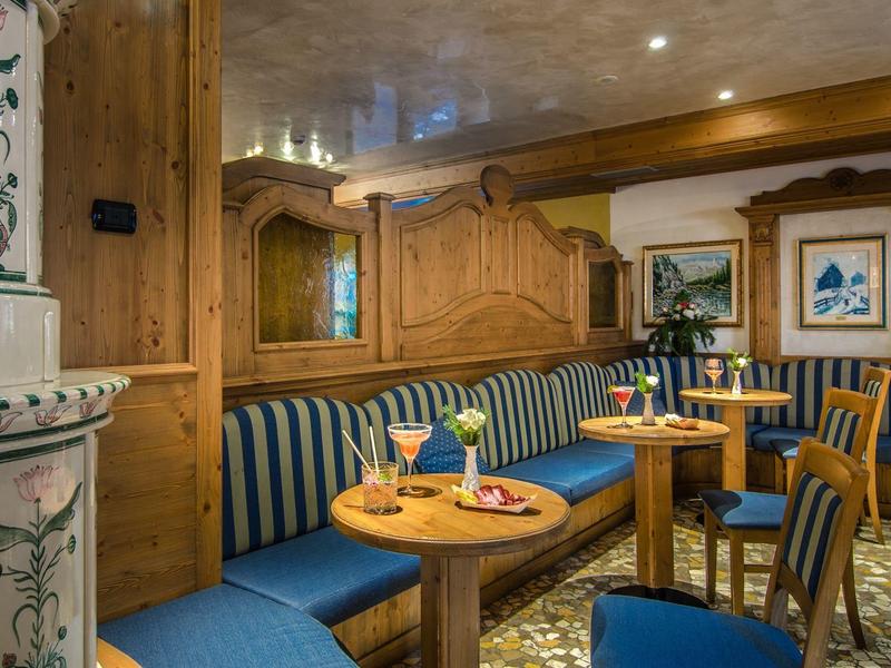 Gemütlicher Gastraum mit Holzvertäfelung, blauen Polstern und dekorativem Kachelofen.