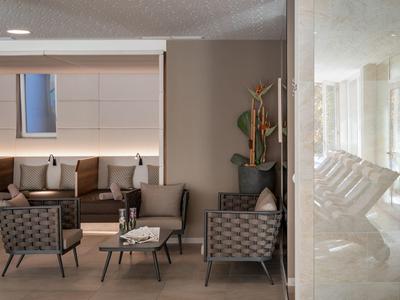 Moderne Lounge mit grauen Sesseln, braunen Kissen und minimalistischen Holzmöbeln, helle Wand mit Fenster.