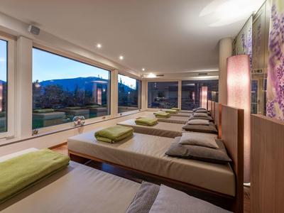 Moderner Ruheraum mit Liegen, grünen Handtüchern und Panoramafenstern mit Bergblick.