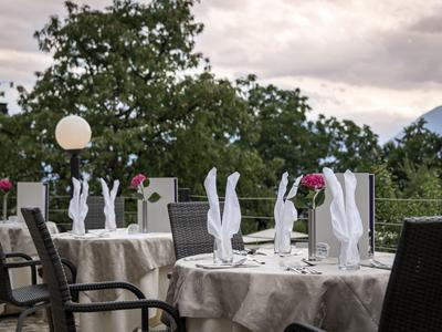 Terrazza esterna con tavoli apparecchiati, tovaglioli bianchi piegati e circondata dalla natura.