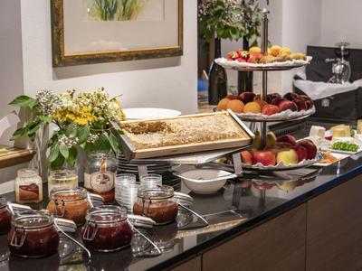 Buffet mit Obst, Gebäck, Marmeladen und Saft auf schwarzer Marmorplatte im hellen Raum.