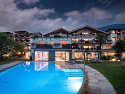 Hotel moderno con piscina illuminata e giardino curato di notte.