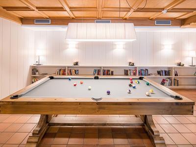 Heller Raum mit einem Billardtisch, Bücherregalen und warmem Holzdekor.