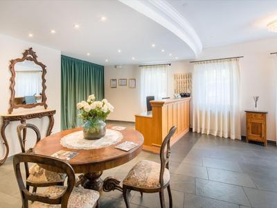 Heller Empfangsbereich mit antiken Holzmöbeln und Rundtisch mit Blumen in einer Vase.