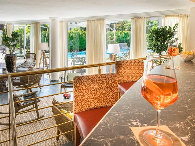 Helles und modernes Wohnzimmer mit großen Fenstern, roten Stühlen und Wein auf Marmor-Tresen.