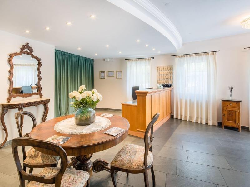 Heller Raum mit rundem Holztisch, vier antiken Stühlen, großem Spiegel und gemütlicher Sitzecke.