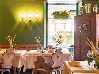 Gemütlicher Gastraum mit grünen Wänden, hellen Holzmöbeln und dekorativer Beleuchtung.