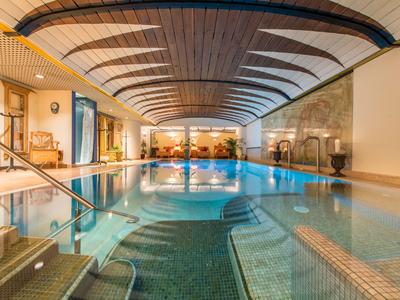 Heated indoor pool with curved wooden ceiling and inviting seating areas in hotel.