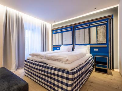 Modernes Schlafzimmer mit Doppelbett, kariertem Bettgestell, blauer Wandgestaltung und großen Vorhängen.